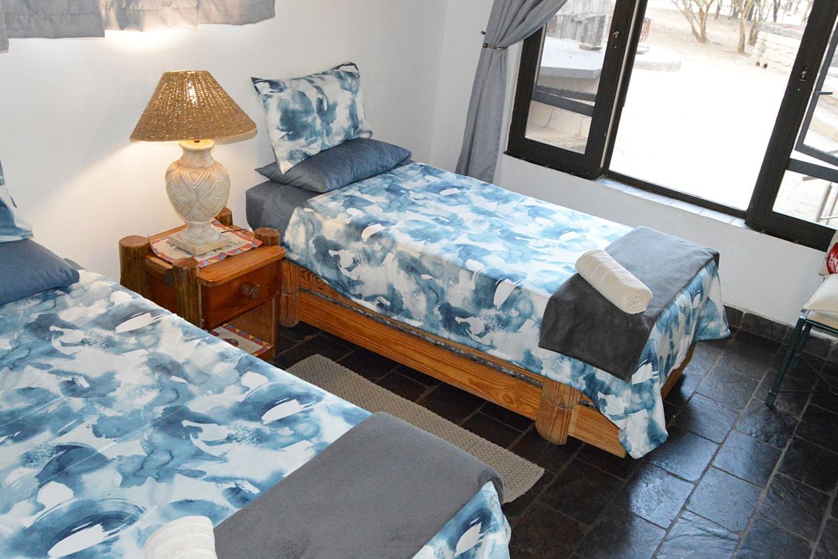 A bedroom featuring dark slate tile flooring and a large window providing natural light.