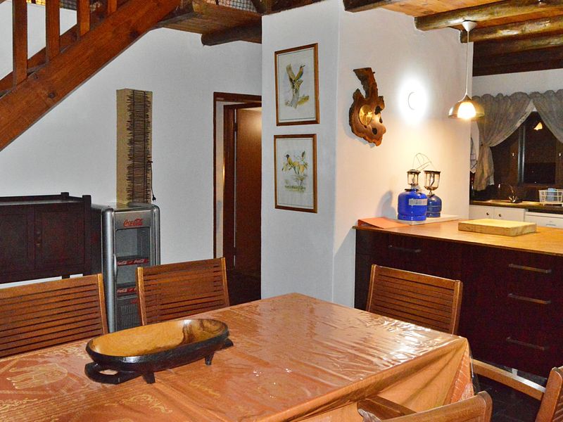 Open plan living and dining area featuring a timber staircase, exposed ceiling beams, and a functional kitchen island with built-in cabinetry.