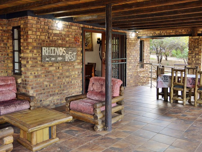 A spacious covered patio featuring rustic facebrick walls, exposed timber beam ceilings, and durable tiled flooring, ideal for outdoor relaxation and entertaining.