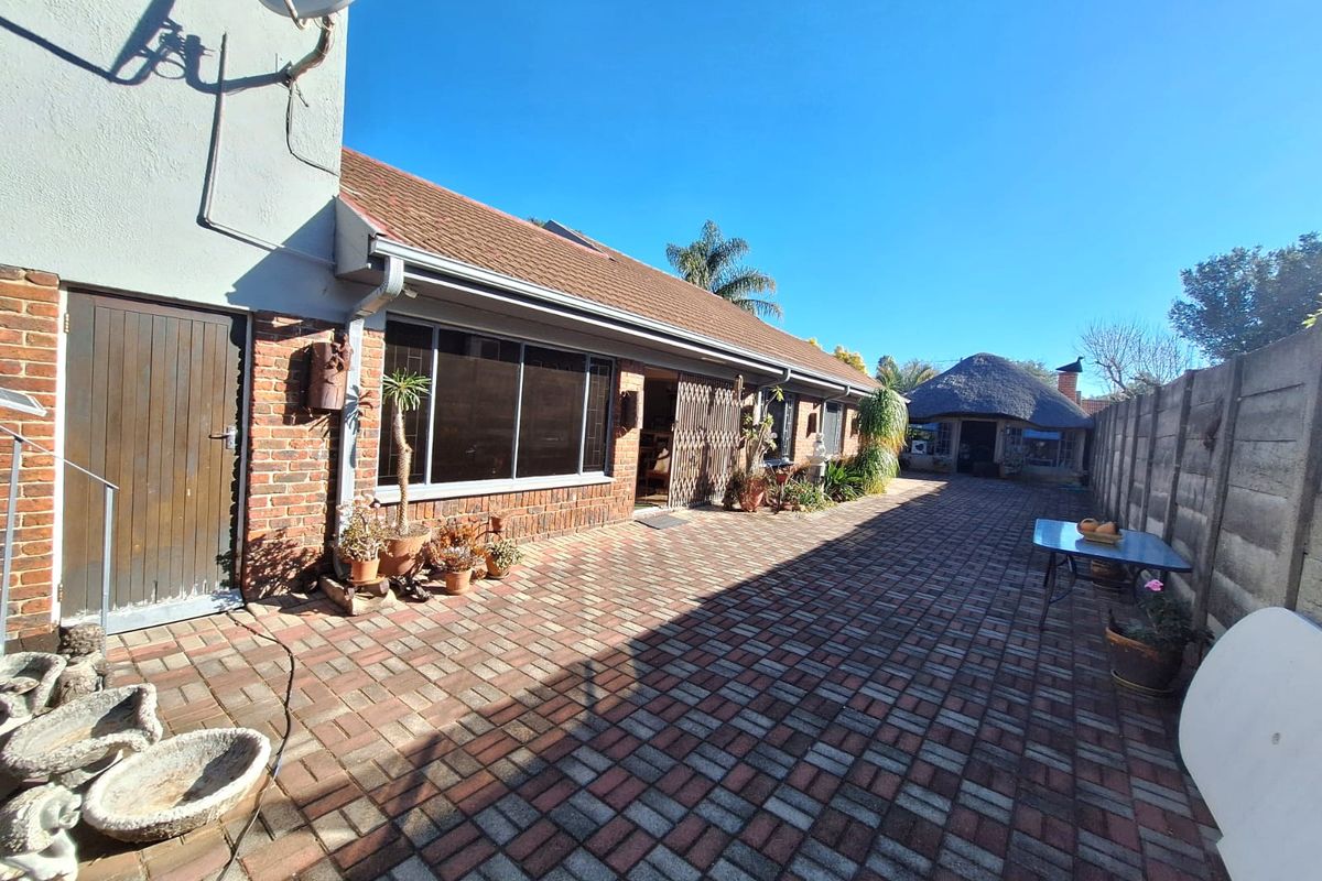 Rear exterior view of the property featuring extensive brick paving, a precast boundary wall, and access to the main dwelling via sliding doors.