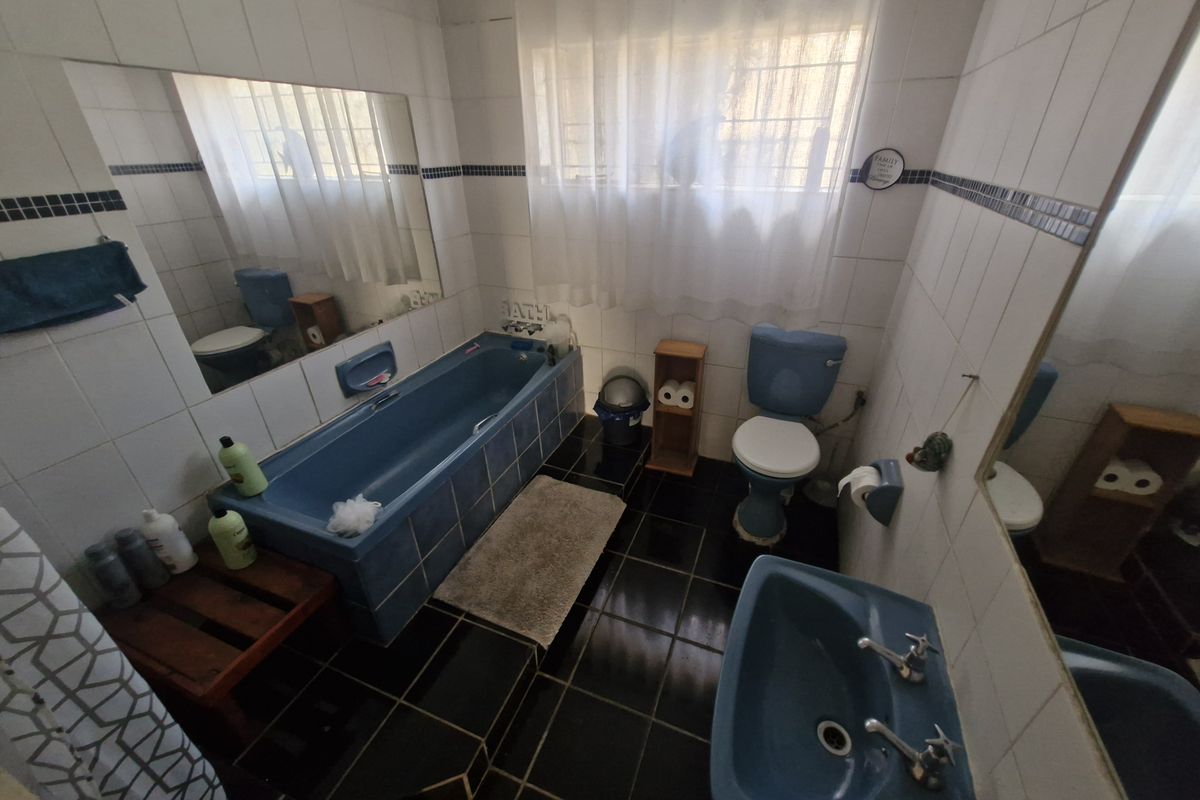 A dated bathroom featuring a blue suite, ceramic wall and floor tiles, and a large wall mirror.