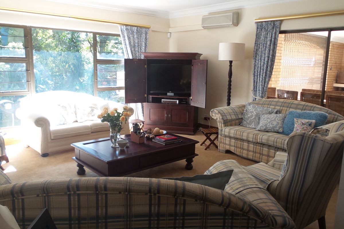 A spacious living room featuring large windows, natural light, and a wall-mounted air conditioning unit, offering a comfortable and functional living space.