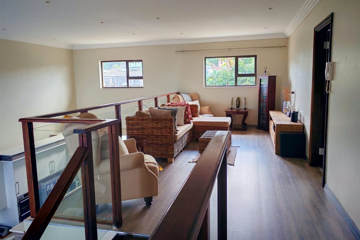 Spacious mezzanine living area featuring timber balustrades, laminate flooring, and recessed downlights, offering a bright and open atmosphere.