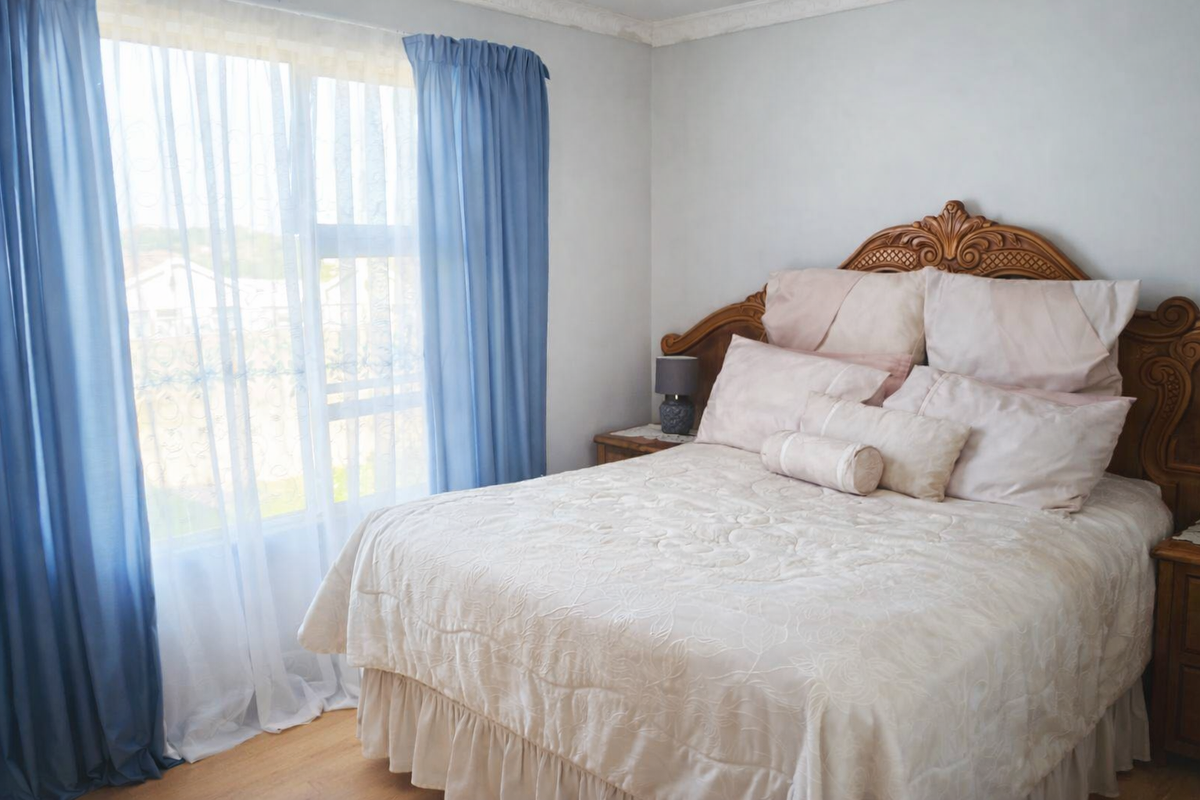 A well-lit bedroom featuring laminate flooring and decorative ceiling cornicing, providing a comfortable and functional living space.