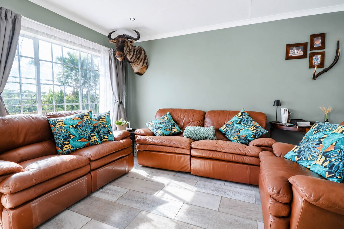 A bright living room featuring large grid-pane windows, tiled flooring, and recessed ceiling lighting, creating a comfortable and well-lit space.