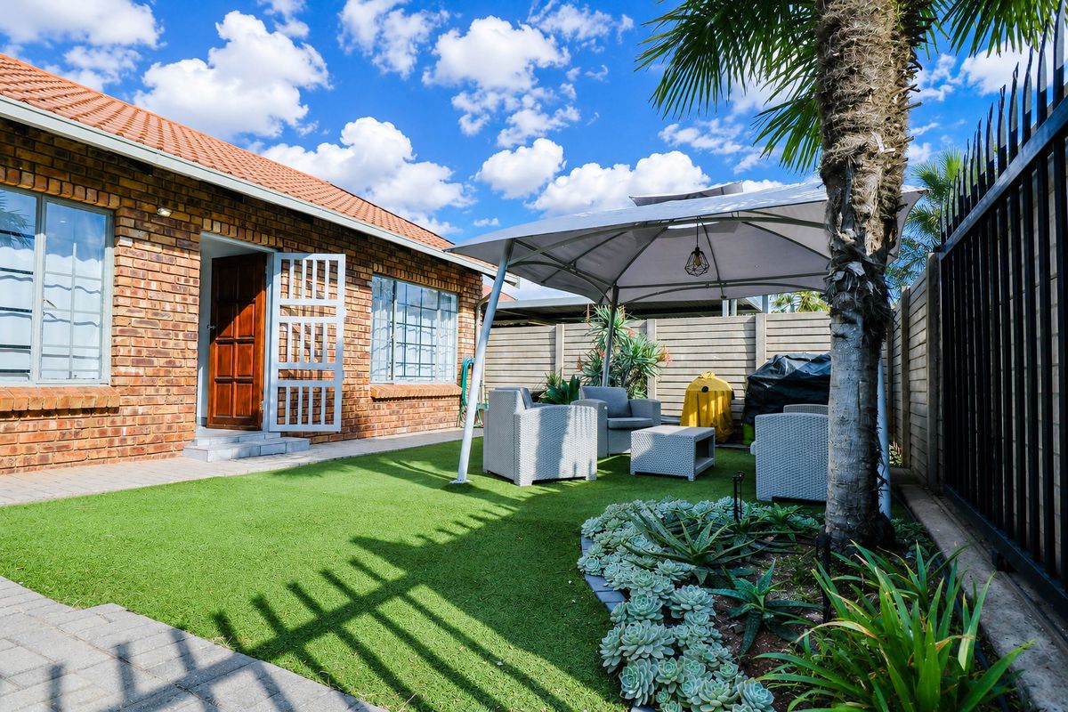 A private rear garden featuring a paved walkway, artificial lawn, and perimeter walling, providing a low-maintenance outdoor space for the townhouse.