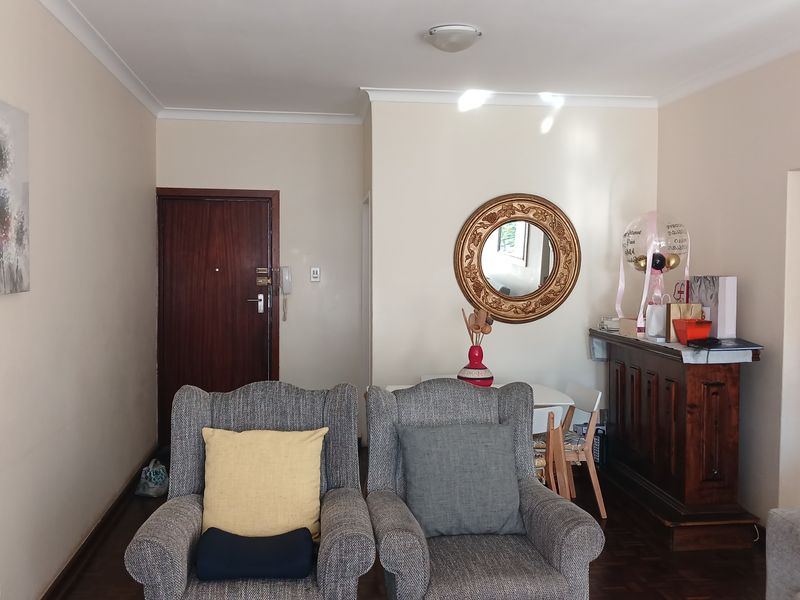 A living room area featuring parquet flooring, a solid timber entrance door, and a built-in wooden sideboard unit.