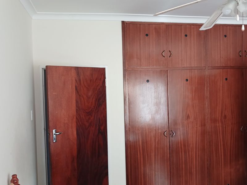 A bedroom featuring built-in wooden cabinetry and a ceiling fan, providing ample storage space.