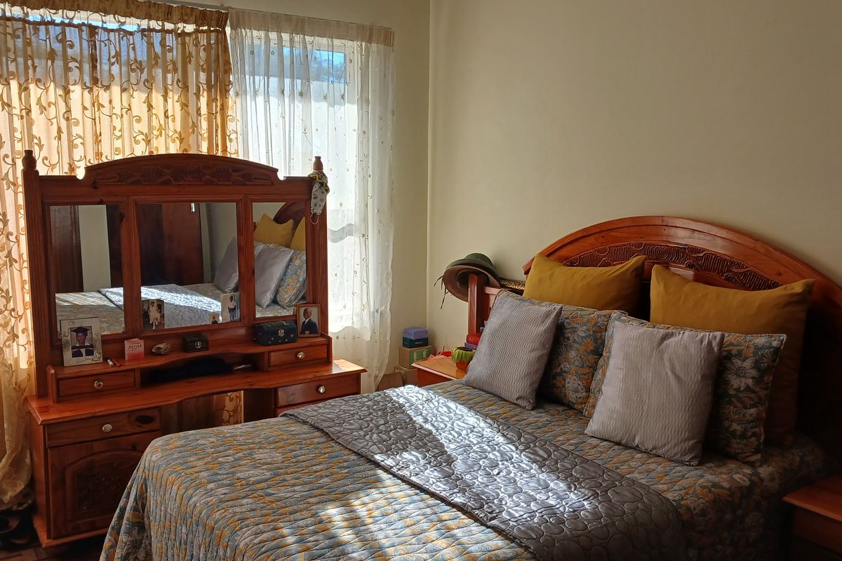 A bedroom featuring large windows with sheer curtains, providing natural light to the space.