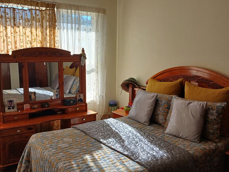 A bedroom featuring large windows with sheer curtains, providing natural light to the space.