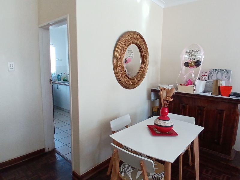A view of the dining area featuring parquet flooring, with a doorway leading into the kitchen and a built-in wooden sideboard.