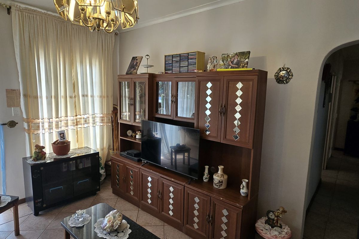 A living room featuring tiled flooring, an arched entryway, and a sliding glass door providing access to the exterior.
