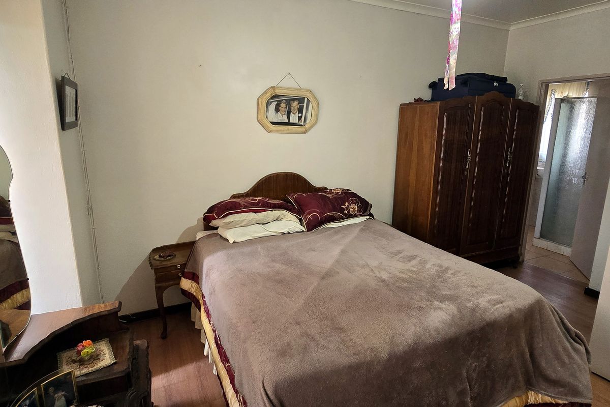 A functional bedroom featuring laminate flooring and direct access to an en-suite bathroom.
