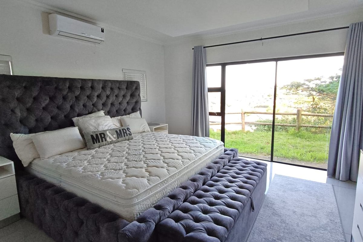 Spacious bedroom featuring tiled flooring, a wall-mounted air conditioning unit, and large sliding glass doors providing direct access to the outdoor area.