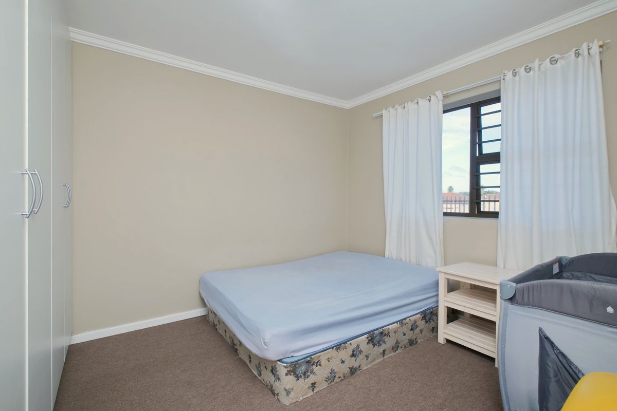 A bedroom featuring neutral wall tones, carpeted flooring, a built-in wardrobe, and a window fitted with security bars.
