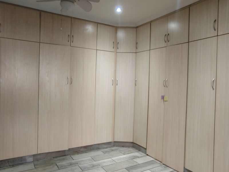 A bedroom featuring extensive wall-to-wall built-in cabinetry, tiled flooring, and a ceiling fan, offering ample storage space.