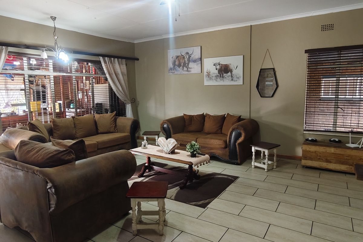 A spacious living room featuring tiled flooring, a large sliding glass door with curtains, and a ceiling fan, providing a comfortable and functional living space.