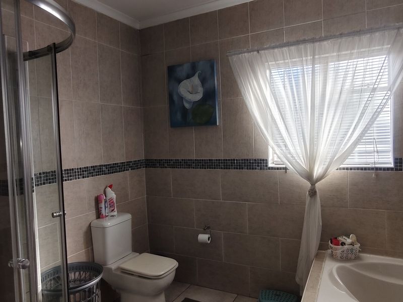 A functional bathroom featuring a shower enclosure, bathtub, and tiled wall finishes with a neutral color palette.