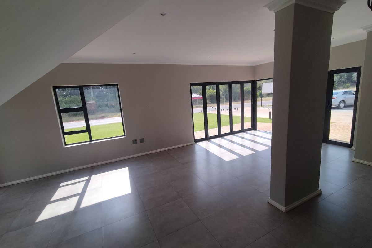 Spacious, open-plan living area featuring large format floor tiles, modern aluminium folding doors, and a neutral color palette with abundant natural light.