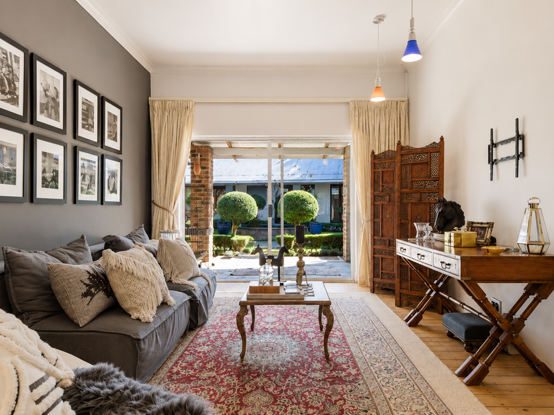 A well-maintained living room featuring hardwood floors, an accent wall, and large sliding glass doors that provide direct access to the rear patio.