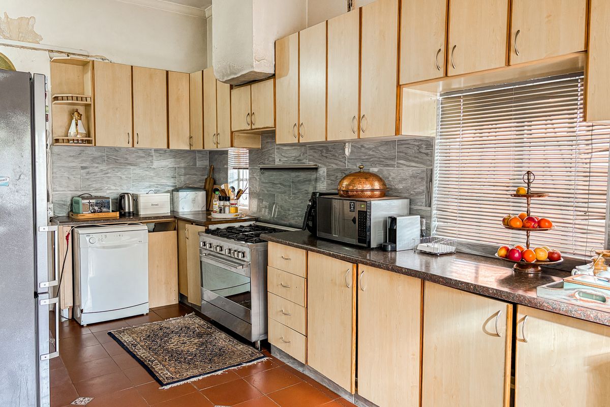 A dated kitchen featuring light wood-finish cabinetry, gas stove, and tiled splashbacks, requiring cosmetic updates to the walls and finishes.