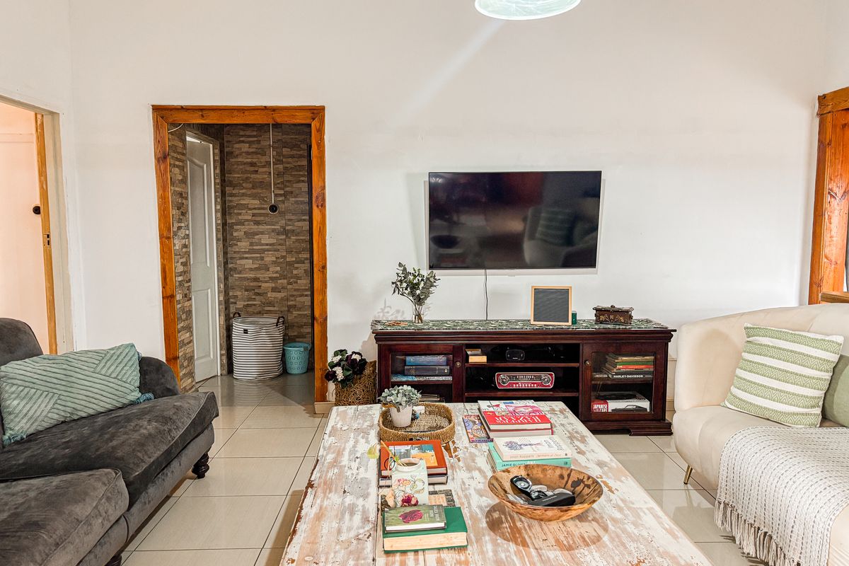 A comfortable living room featuring tiled flooring, timber door frames, and a wall-mounted television, providing a functional and inviting space.
