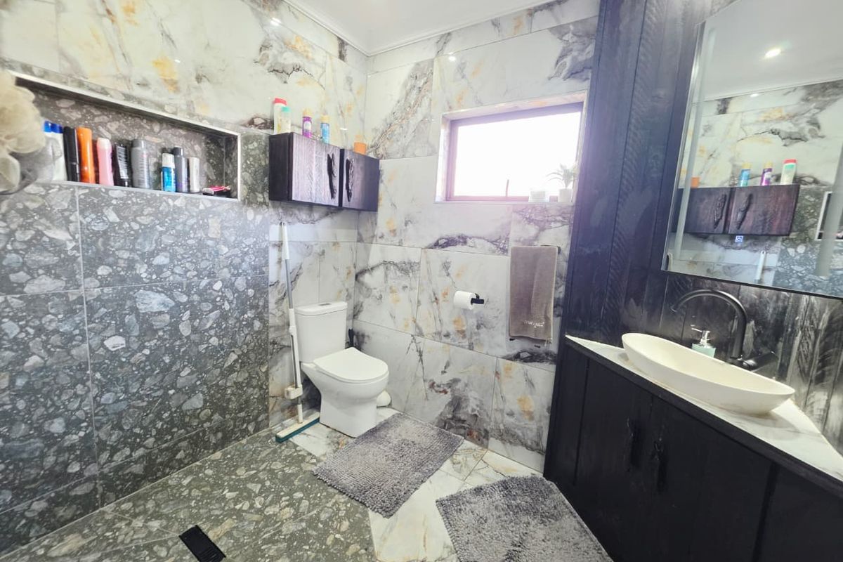 Modern bathroom featuring a walk-in shower with a recessed niche, dark wood vanity with a vessel sink, and contemporary marble-effect wall tiling.