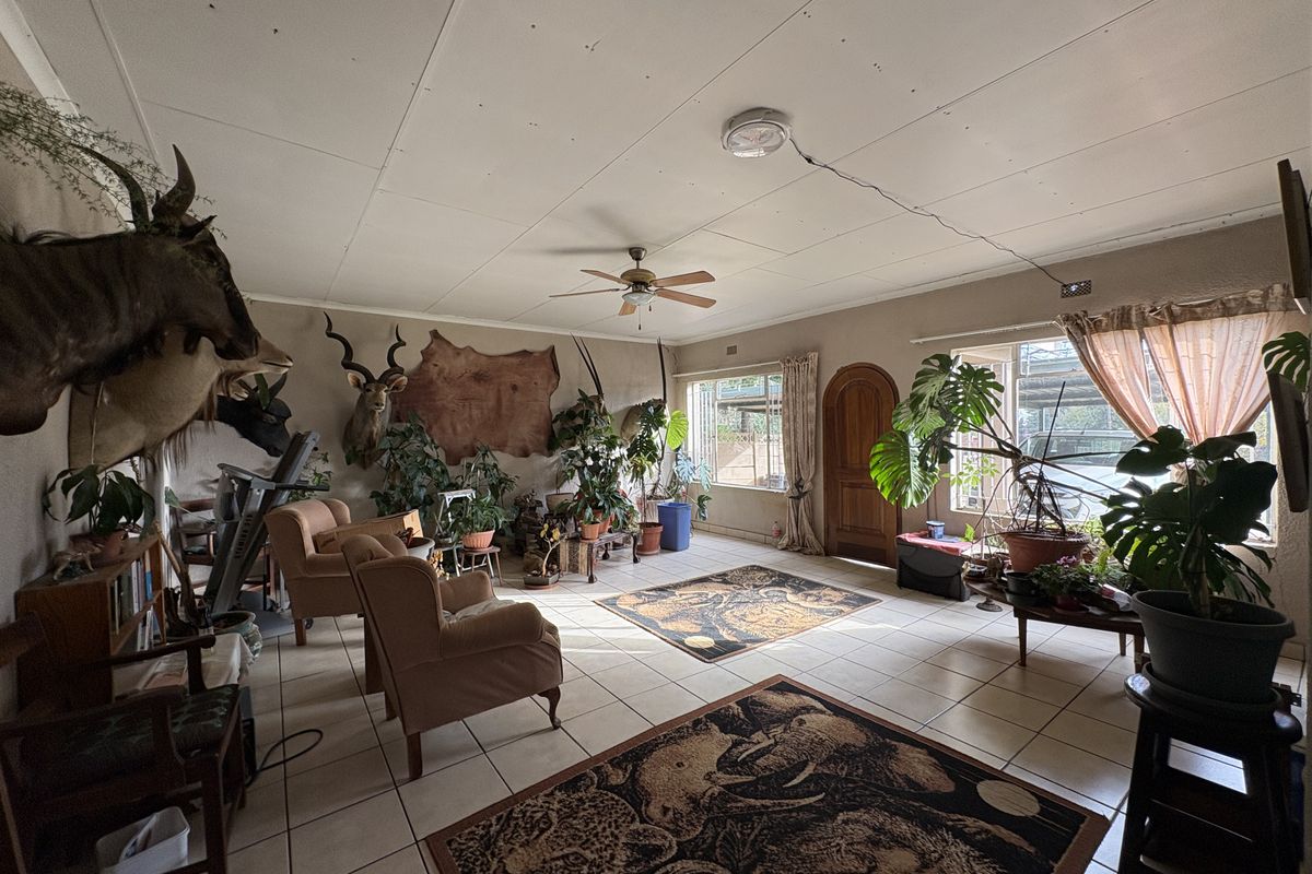 Spacious living area featuring tiled flooring, a ceiling fan, and large windows, offering a bright layout with potential for modern updates.