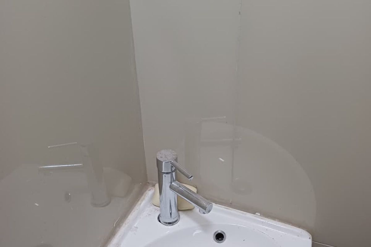 A compact corner basin featuring a chrome mixer tap and decorative mosaic tile splashback, suitable for a small powder room or ensuite.