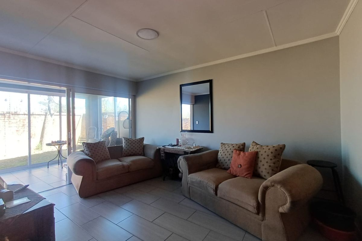 A comfortable living room featuring tiled flooring and a large sliding glass door that provides direct access to the outdoor patio area.