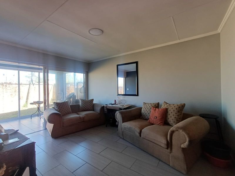 A comfortable living room featuring tiled flooring and a large sliding glass door that provides direct access to the outdoor patio area.