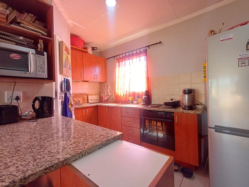 A functional kitchen featuring granite countertops, built-in cabinetry, and integrated cooking appliances, offering a practical layout for daily meal preparation.