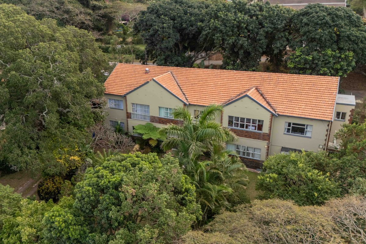 Aerial view of a multi-story residential flat building featuring a terracotta tiled roof and established surrounding garden greenery.