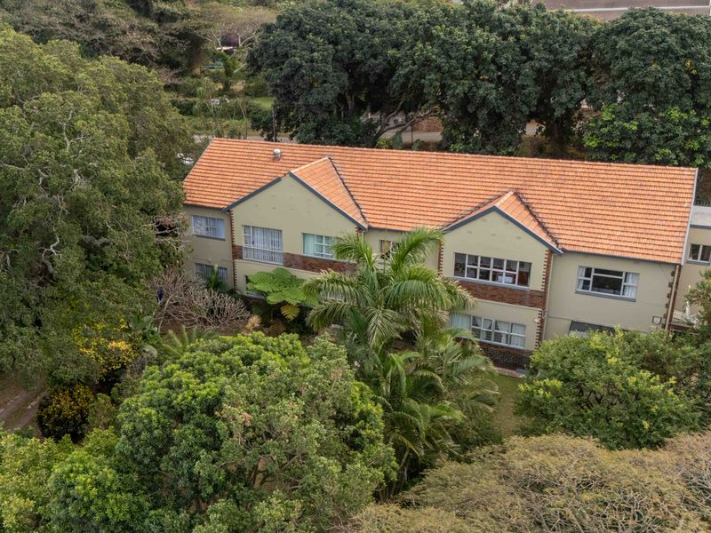 Aerial view of a multi-story residential flat building featuring a terracotta tiled roof and established surrounding garden greenery.