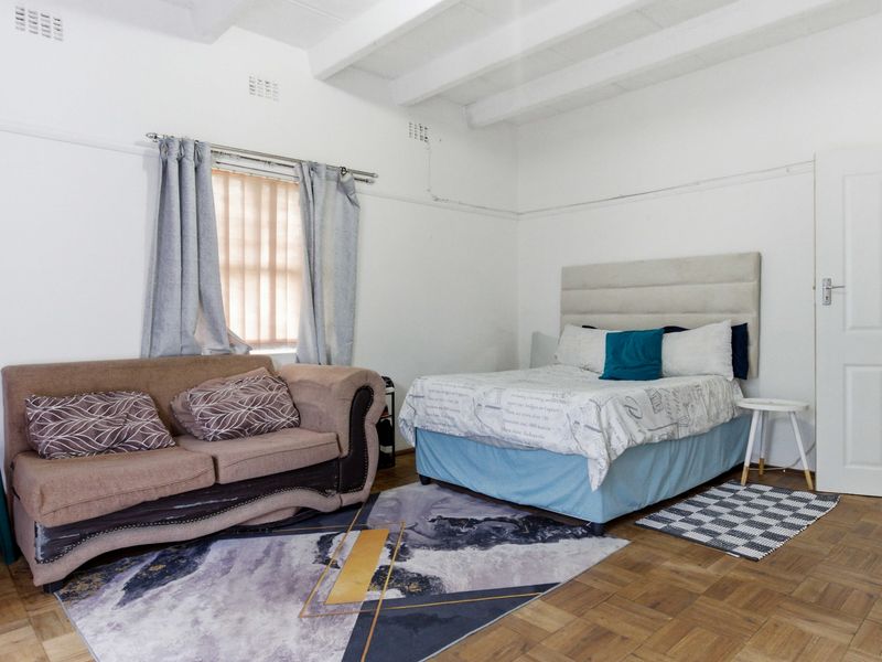 Spacious bedroom featuring classic parquet flooring and exposed ceiling beams, offering a neutral canvas for personalization.