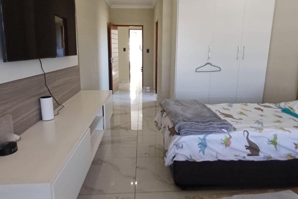 A well-maintained bedroom featuring modern tiled flooring, built-in cupboards, and a sleek floating media console.