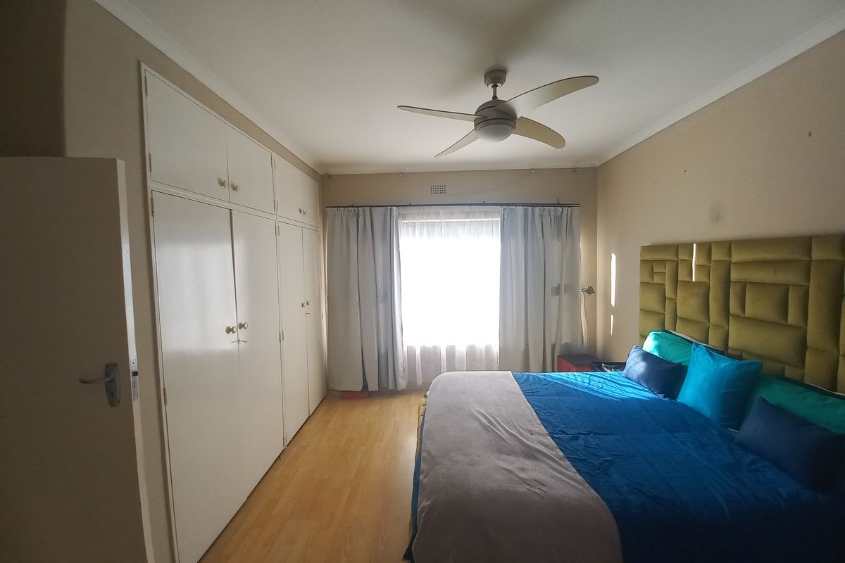 A bedroom featuring laminate flooring, a ceiling fan, and extensive built-in cupboard storage.