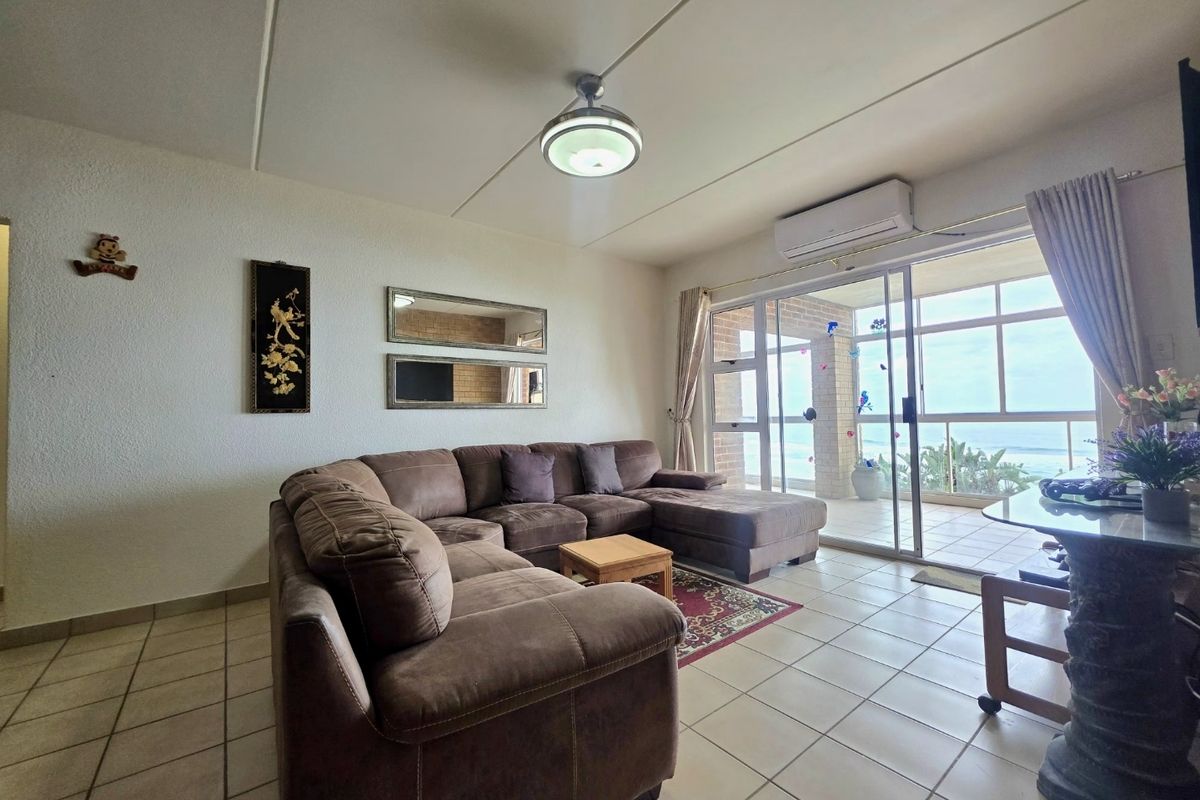 A spacious living room featuring tiled floors, a ceiling fan, and split-system air conditioning, with direct access to a balcony offering scenic views.