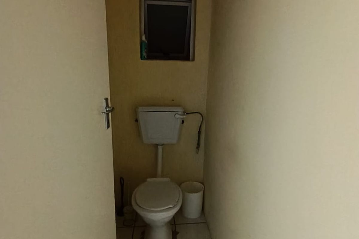 A compact, dated guest toilet featuring ceramic floor tiles and a small ventilation window, requiring cosmetic updates to improve its overall condition.