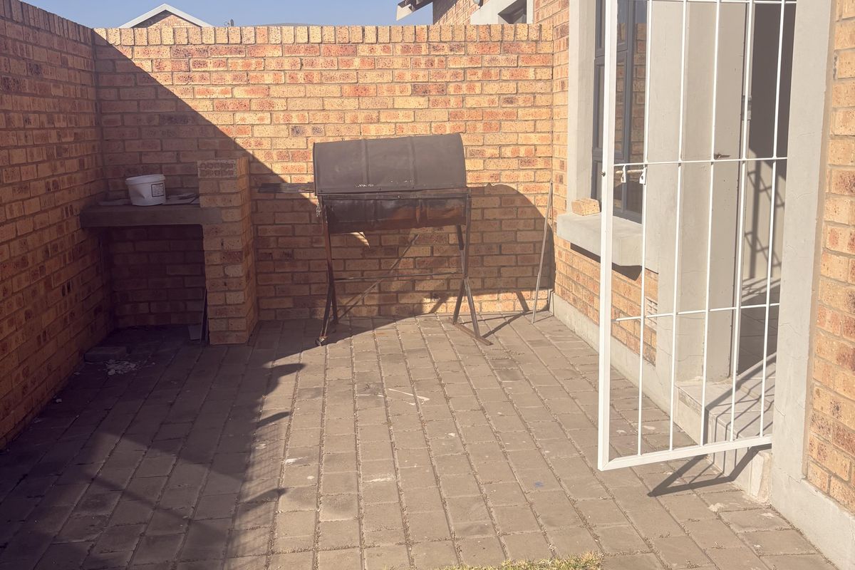 A private rear courtyard featuring face-brick walls, paved flooring, and a built-in concrete prep counter, providing a functional outdoor space.
