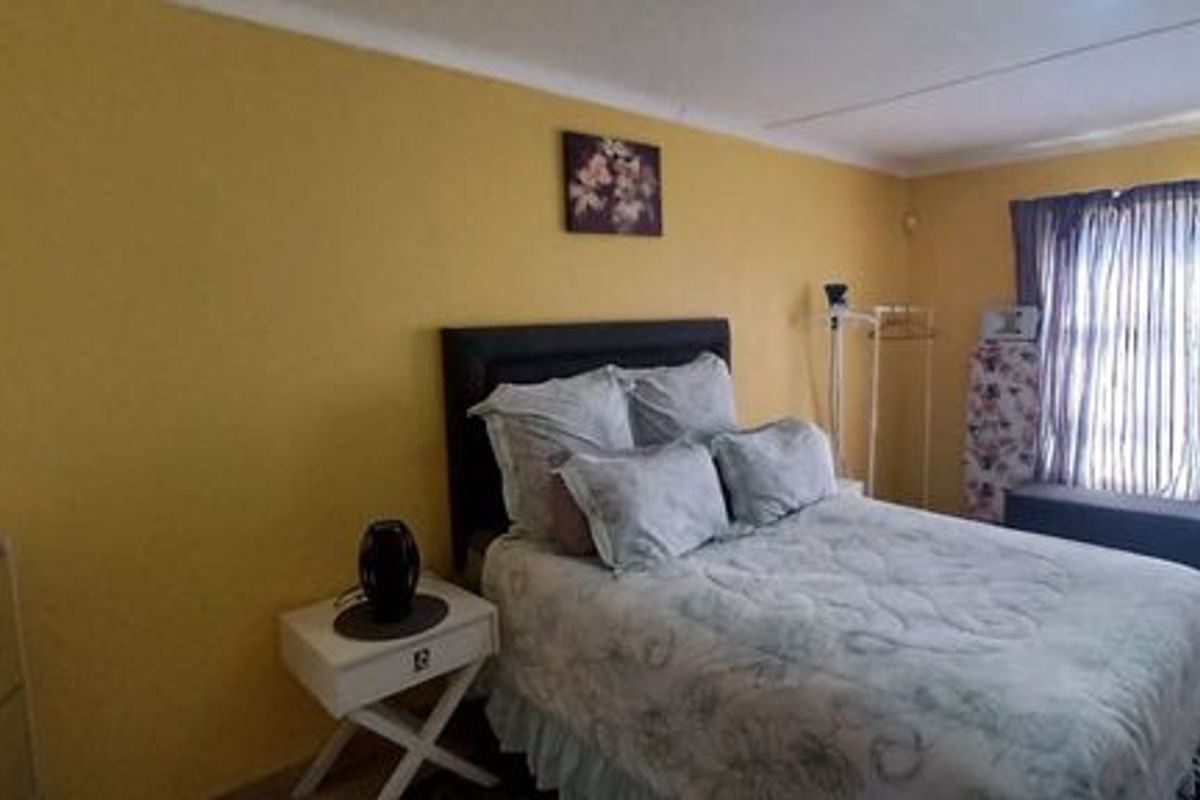 A standard bedroom featuring tiled flooring and large windows with curtain rails, providing a functional and well-lit living space.