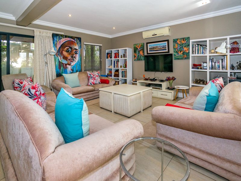 A comfortable living room featuring tiled flooring, recessed ceiling lighting, crown molding, and a wall-mounted air conditioning unit.