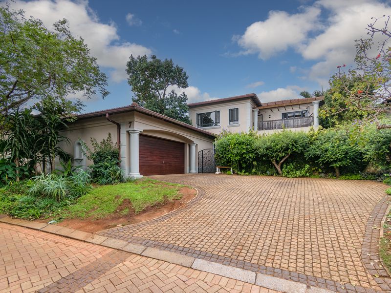 A well-maintained double-story residential property featuring a paved driveway, integrated garage, and established garden landscaping.
