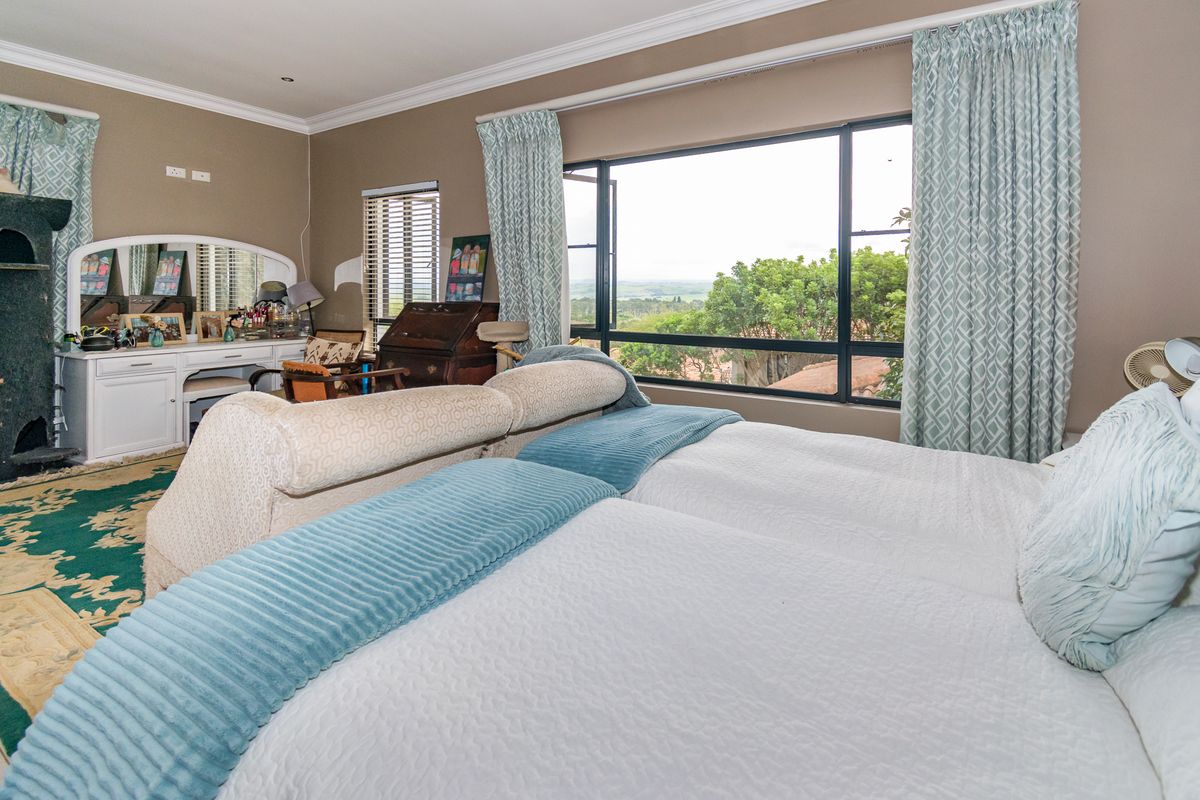 Spacious bedroom featuring large windows with scenic views, crown molding, and neutral wall finishes.