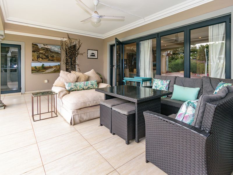 A spacious covered patio featuring tiled flooring, a ceiling fan, and large glass folding doors providing seamless access to the interior living space.