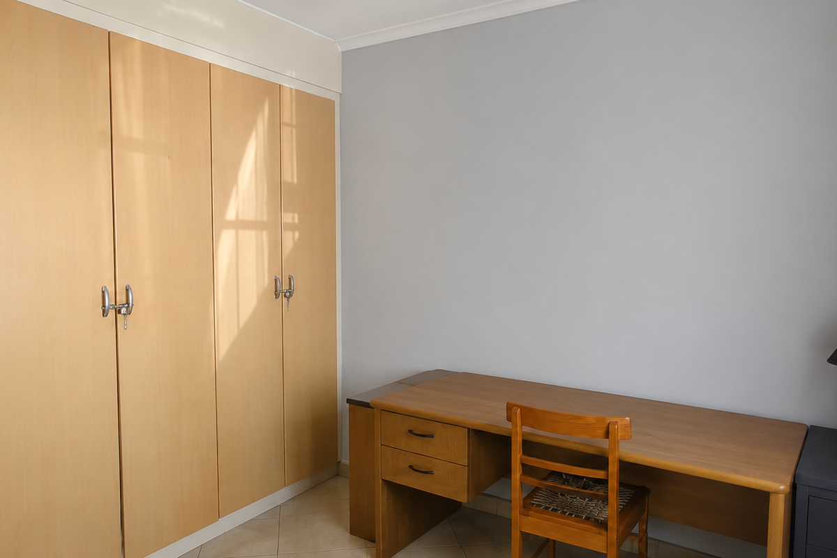 A bedroom featuring light-toned built-in wardrobes, neutral wall finishes, and tiled flooring, providing a functional and well-maintained space.