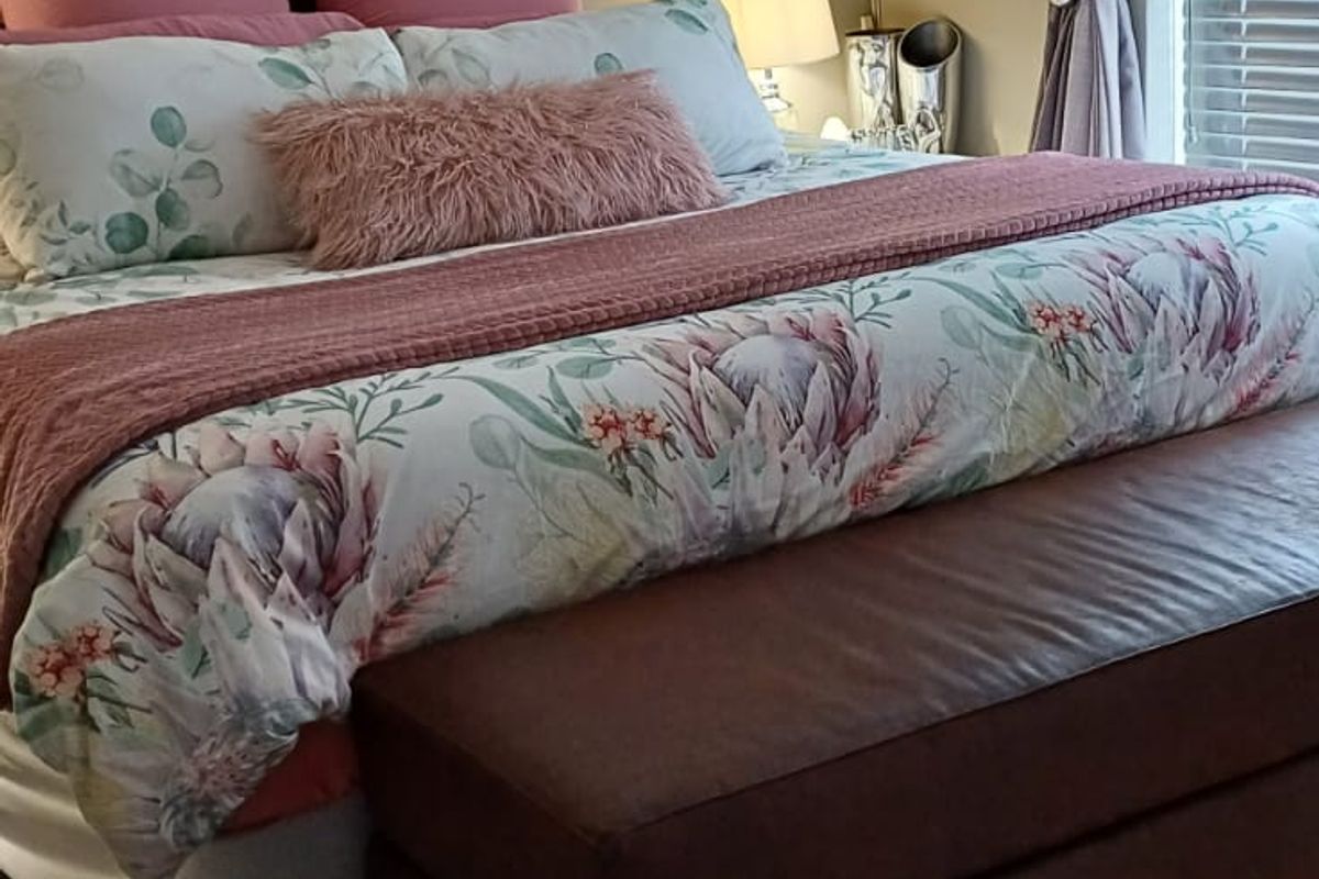 A well-maintained bedroom featuring laminate flooring, a split-system air conditioner, and venetian blinds, offering a comfortable and functional living space.