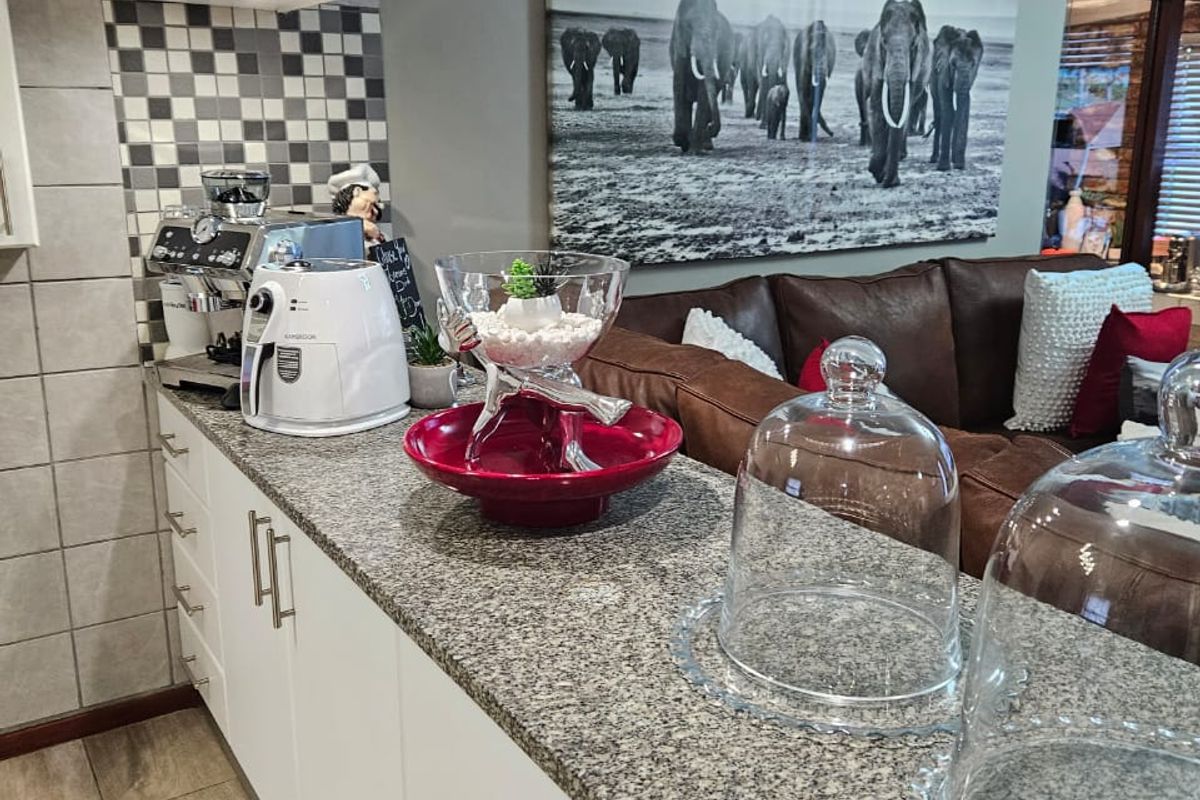 A well-maintained kitchen featuring white cabinetry, granite countertops, and a modern tiled backsplash, seamlessly connecting to the adjacent living area.
