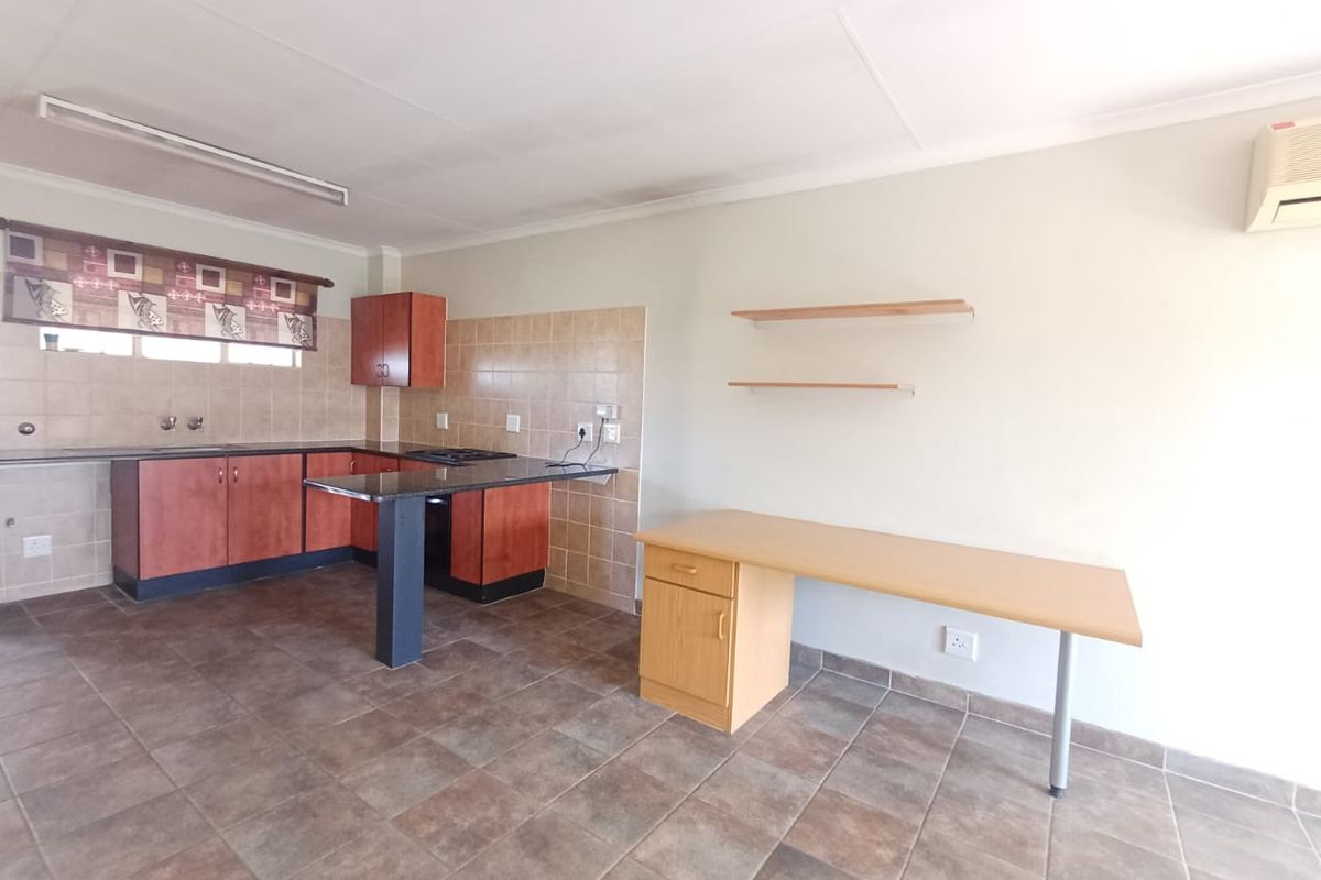 A functional kitchen featuring built-in cabinetry, granite countertops, tiled backsplash, and ceramic flooring, offering a practical layout for daily use.