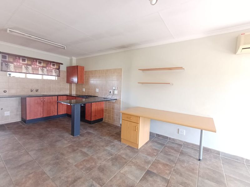 A functional kitchen featuring built-in cabinetry, granite countertops, tiled backsplash, and ceramic flooring, offering a practical layout for daily use.